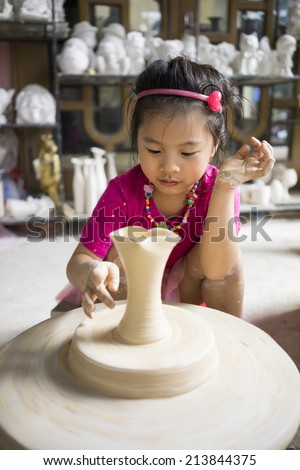 Hanoi, Vietnam - Mar 30, 2014: Unidentified little girl learn to form a lottery product in Bat Trang ancient pottery village, Hanoi, Vietnam