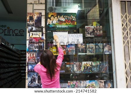 Hanoi, Vietnam - Mar 29, 2014: Unidentified woman tear off advertising paper showing new coming DVD