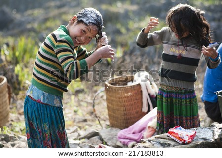 Ha Giang, Vietnam - Feb 16, 2013: Unidentified Hmong children washing their hair with family at a nature water well