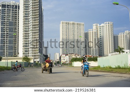 Hanoi, Vietnam - Sept 21, 2014: People on traffic in outskirts street of Hanoi city, with high buildings on background