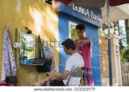 Hanoi, Vietnam - Sept 14, 2014: Unidentified man has his hair cut by barber in a small hairdresser by ATM on Le Dai Hanh st, Hanoi