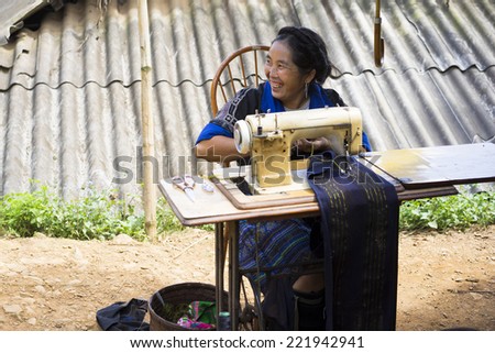 Yen Bai, Vietnam - Sept 27, 2014: Unidentified H\'mong woman making clothes by sewing machine nearby her house