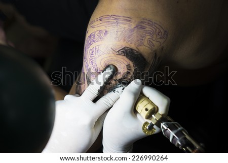 Hanoi, Vietnam - Oct 29, 2014: Tattoo artist makes a tattoo on a man arm