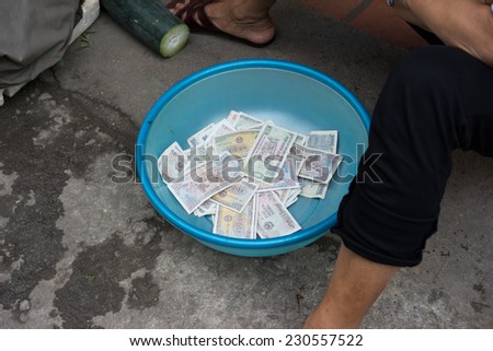 Vietnamese small change paper money in plastic basin of a vegetable vendor in Hanoi