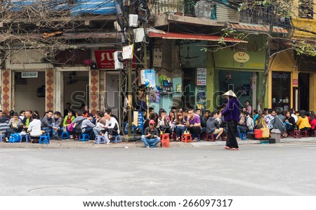 Hanoi, Vietnam - Mar 15, 2015: People drink coffee, tea or juice fruit on cafe stall on sidewalk in Nha Tho street, center of Hanoi. Drinking on street is a typical culture of Hanoi