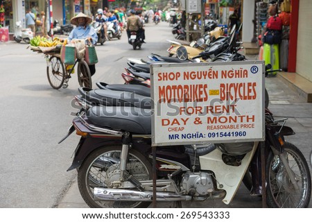 Hanoi, Vietnam - Apr 5, 2015: Advertising sign plate motorbikes for rent in Hang Bac street. Motorbike is most popular and cheapest transport in Hanoi. A vendor walking on background