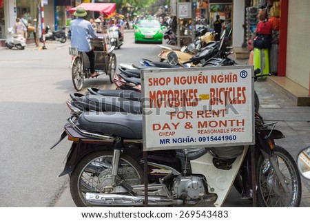 Hanoi, Vietnam - Apr 5, 2015: Advertising sign plate motorbikes for rent in Hang Bac street. Motorbike is most popular and cheapest transport in Hanoi. Pedicab running on background