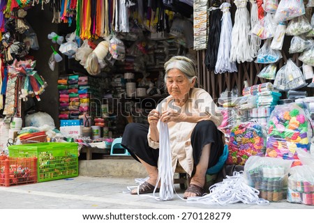 Hanoi, Vietnam - Apr 5, 2015: Old Vietnamese woman working in a clothing accessory store in Hang Bo street, Hanoi
