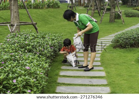 Hanoi, Vietnam - Apr 19, 2015: Team of family volunteers picking up litter in the park at Times City, a luxury and high class combination of apartment and mega mall retail center in Hanoi