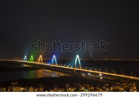 Nhat Tan cable-stayed bridge crossing the Red River  in Hanoi at night. Lighting flashes after heavy rain