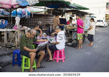 Bangkok, Thailand - June 28, 2015: Old men reading newspaper at a tea stall on Bangkok street