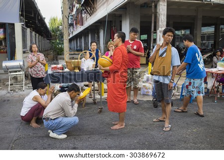 Bangkok, Thailand - June 28, 2015: People praying respect to monk on Bangkok street.  Roughly 95% of the Thai people are practitioners of Theravada Buddhism, the official religion of Thailand
