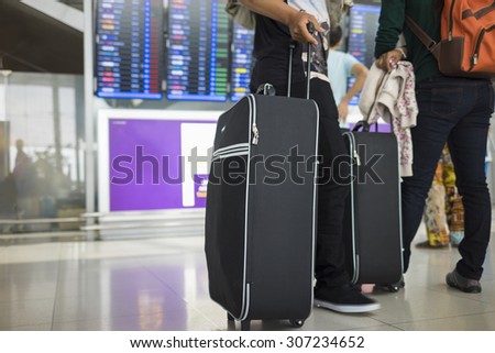 Travelling suitcase against flight information board on background. Concept of travel by airplane
