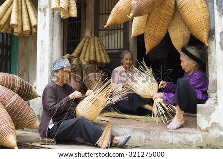 Hung Yen, Vietnam - July 26, 2015: Old women weaves bamboo fish trap at Vietnamese traditional crafts village Thu Sy, Hung Yen province.