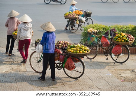 Vietnamese vendors with tropical fruit loaded basket on bike