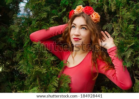 Girl with roses.Girl in pink clothes with a wreath of roses on her head stay at juniper