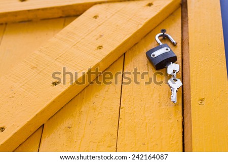 Lock hanging on yellow wooden door