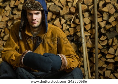 Young russian woodcutter in village. Fire wood background