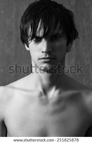 Portrait of handsome man with wet hair on gray wall background. Black and white portrait.