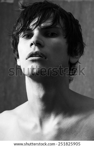 Portrait of handsome man with wet hair on gray wall background. Black and white portrait.