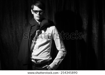 Handsome young man in business suit stay on drapes background. Holding jacket. Black and white portrait.