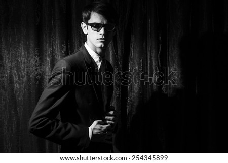 Handsome young man in business suit stay on drapes background. Black and white portrait.