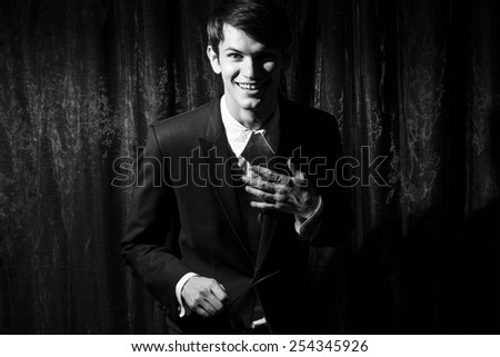 Handsome young man in business suit stay on drapes background. Laughing. Black and white portrait.