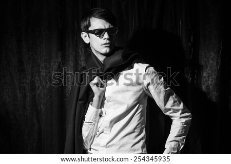 Handsome young man in business suit stay on drapes background. Holding jacket. Black and white portrait.