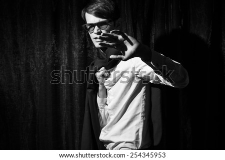 Handsome young man in business suit stay on drapes background. Closed hand. Black and white portrait.