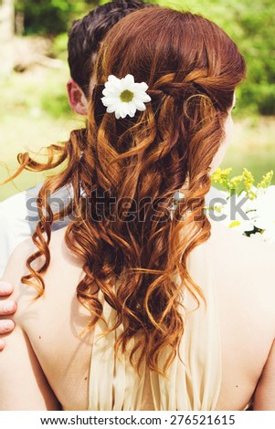 Wavy hair of bride with flower in her hairstyle.