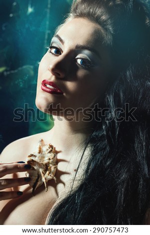 Head shot of young beautiful,woman with shell in arms.