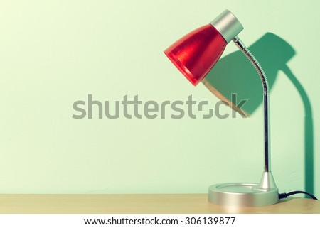 Books and red lamp on wood table.