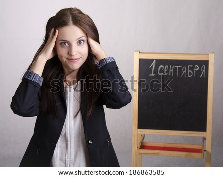 School teacher holding his head thinking that on September 1 will bring many new problems. In the background stands Board