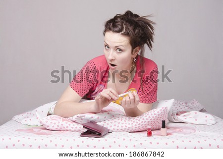 A young girl lying in bed and saws, nails nail files