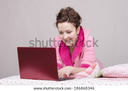 The girl lying in bed and works in the laptop