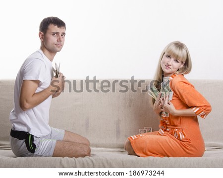 Young couple sitting on the couch, facing each other. They divided salary, each bale presses his part to himself