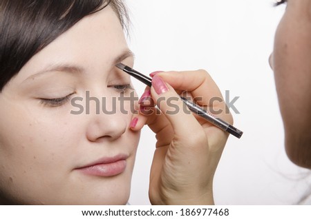 Makeup artist deals makeup on the model\'s face. She leads eyebrow pencil model.