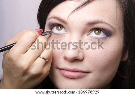 Makeup artist deals makeup on the model\'s face. She paints eyelashes model.
