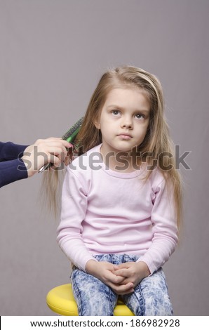 Hairdresser brushing her long hair five year old girl