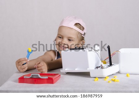 Girl playing in the repairer and repairs toy microwave. A girl Holding a wrench nut and smiles