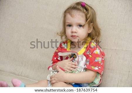 A little girl sits on the couch. To itself the girl pressed a few handkerchiefs not wanting to give them to anyone
