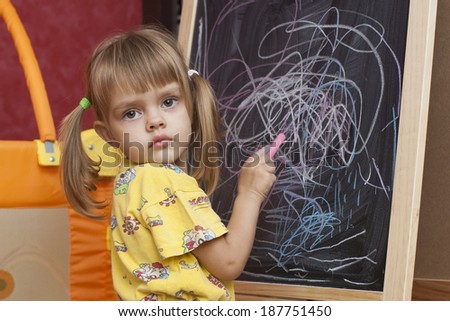 Sad girl draws by a chalk on the easel Doodle. The girl turned around to face the audience and looks in the frame
