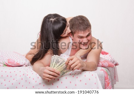 Young couple with money lying in bed