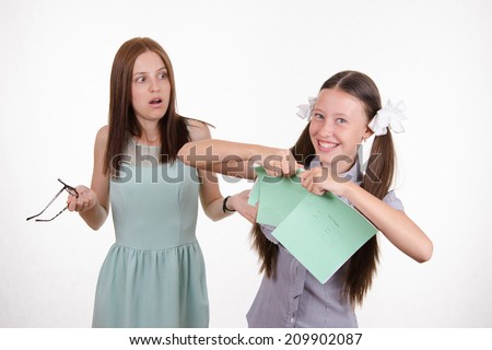 Schoolgirl having fun tearing the notebook in front of an angry teacher