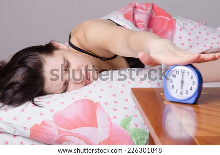 Woman asleep in bed, standing beside an alarm clock on the table, the places on the six o\'clock