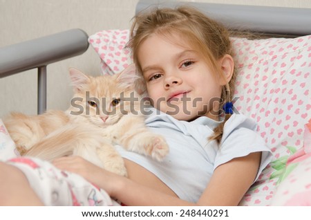 Six year old girl lying in bed with a young cat