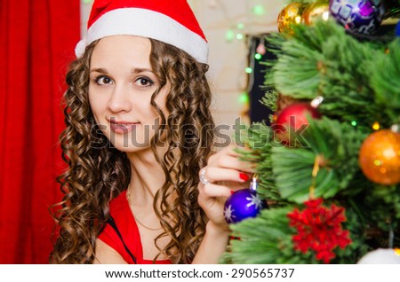 Young beautiful girl decorates Christmas tree toys