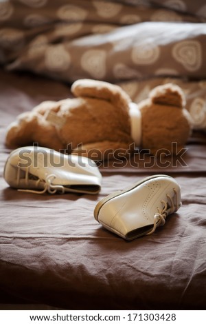 Abandoned shoes and teddy bear in bed