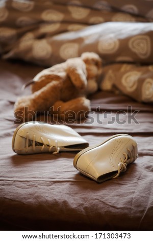 Abandoned shoes and teddy bear in bed