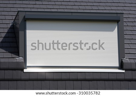 Porthole with a white rolling shutter on a black roof